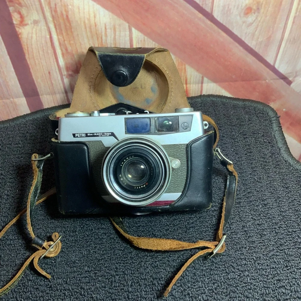 Vintage Petri camera with leather strap and cover.